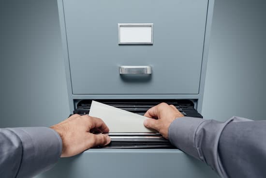 Office clerk searching for files in the filing cabinet, data storage and archives concept, personal point of view